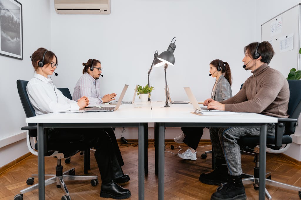 Call center team working with laptops and headsets in a modern office setting.
